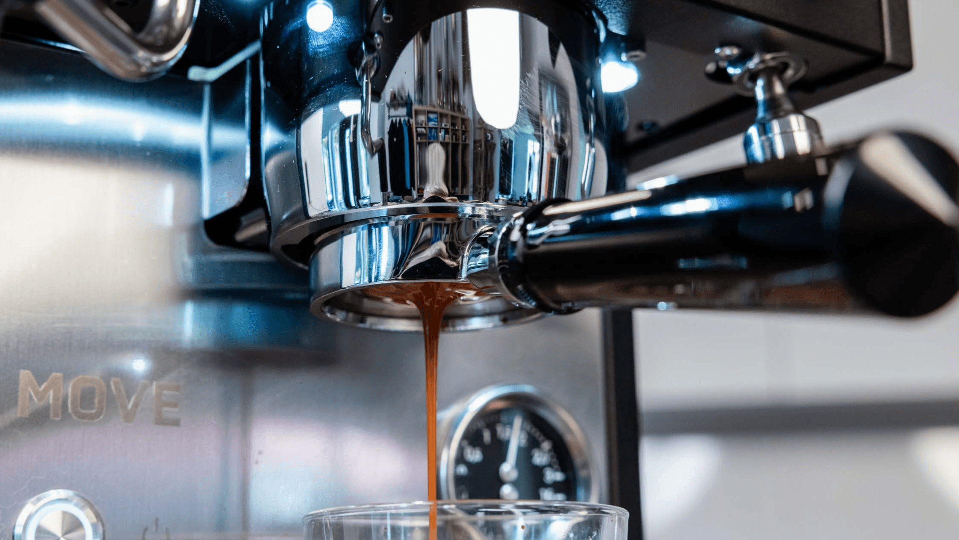 Espresso läuft aus chromatischem Siebträger der Profitec Move 2.0 in Tasse, glänzende Metalloberfläche und Armatur sichtbar