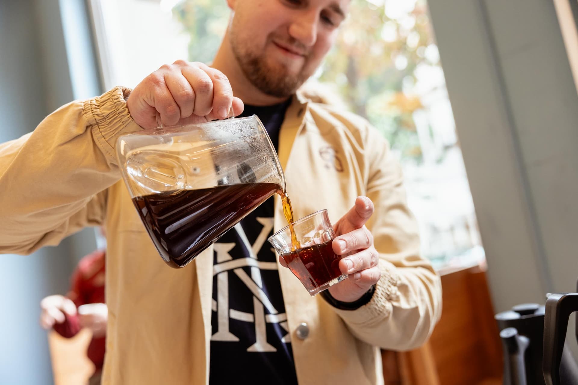 Barista gießt frisch zubereiteten Filterkaffee aus Kanne in Glas bei La Bohème Takeover in Prag