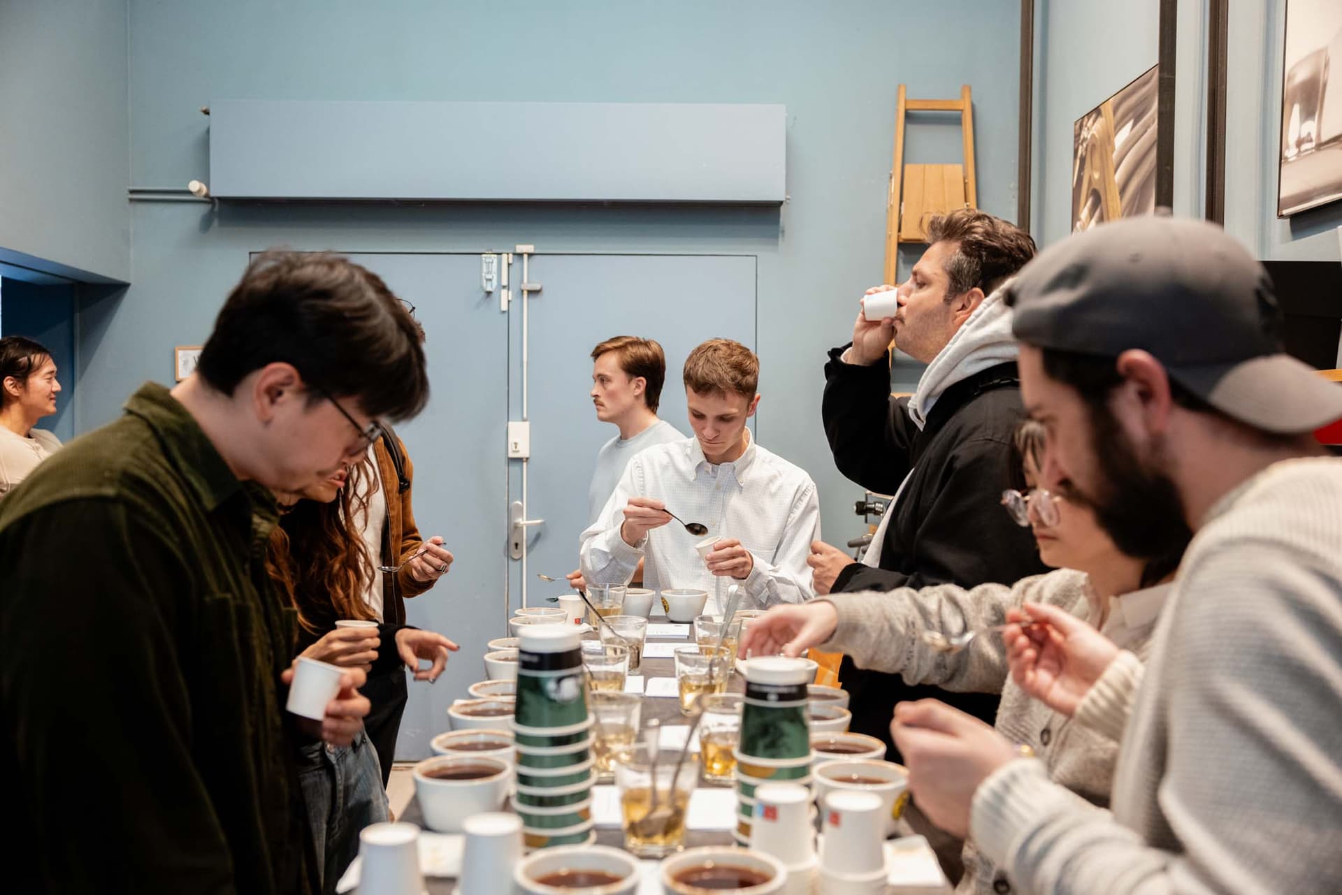 Menschen bei Kaffeeverkostung an einer Bar in Prag, Tassen, Becher und Löffel auf einem langen Verkostungstisch
